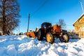 Lyashki, Russia - February 23, 2018: Old tractor removes snow in winter on the street of a traditional Russian village