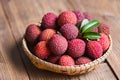 Lychee frui with green leaf on basket wooden background, fresh ripe lychee peeled from lychee tree at tropical fruit Thailand in