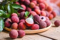 Lychee frui with green leaf on wooden plate background , fresh ripe lychee peeled from lychee tree at tropical fruit Thailand in