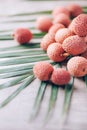 Lychee fruits with palm leaves on rattan background. Copy space. Exotic litchi, lichee fruits. Tropical food concept