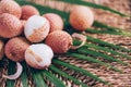 Lychee fruits with palm leaves on rattan background. Copy space. Exotic litchi, lichee fruits. Tropical food concept