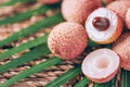 Lychee fruits with palm leaves on rattan background. Copy space. Exotic litchi, lichee fruits. Tropical food concept