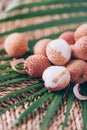 Lychee fruits with palm leaves on rattan background. Copy space. Exotic litchi, lichee fruits. Tropical food concept