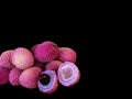 Lychee- small rounded fruit with sweet white scented flesh, a large central stone, and thin rough skin- on black background.