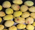 Lychee- small rounded fruit with sweet white scented flesh, a large central stone, and a thin rough skin- on brown wooden