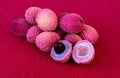 Lychee- small rounded fruit with sweet white scented flesh, a large central stone, and a thin rough skin- on red cloth napkin on t