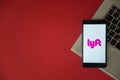 Lyft logo on smartphone screen placed on laptop keyboard.