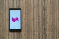 Lyft logo on smartphone screen on wooden background.