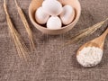 Spikes of wheat, spoon with flour and eggs on burlap