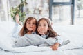 Lying down on bed and looking at the camera. Two cute little girls indoors at home together. Children having fun Royalty Free Stock Photo