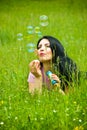 Lying in field and blowing soap bubbles Royalty Free Stock Photo