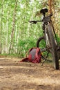 a lying hiking backpack lying next to a bicycle on the ground on a forest path in a coniferous thicket Royalty Free Stock Photo