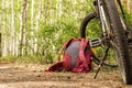a lying hiking backpack lying next to a bicycle on the ground on a forest path in a coniferous thicket Royalty Free Stock Photo
