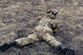 Lying Ukrainian soldier disguises in steppe against of background of dry grass