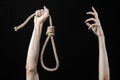 Lynching and suicide theme: man's hand holding a loop of rope for hanging on black isolated background