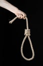 Lynching and suicide theme: man's hand holding a loop of rope for hanging on black isolated background Royalty Free Stock Photo