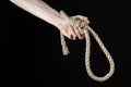 Lynching and suicide theme: man's hand holding a loop of rope for hanging on black isolated background Royalty Free Stock Photo