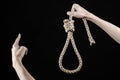 Lynching and suicide theme: man's hand holding a loop of rope for hanging on black isolated background Royalty Free Stock Photo