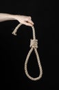 Lynching and suicide theme: man's hand holding a loop of rope for hanging on black isolated background Royalty Free Stock Photo