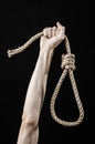 Lynching and suicide theme: man's hand holding a loop of rope for hanging on black isolated background Royalty Free Stock Photo