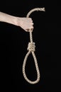 Lynching and suicide theme: man's hand holding a loop of rope for hanging on black isolated background