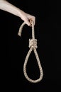 Lynching and suicide theme: man's hand holding a loop of rope for hanging on black isolated background Royalty Free Stock Photo