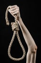 Lynching and suicide theme: man's hand holding a loop of rope for hanging on black isolated background Royalty Free Stock Photo