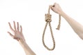 Lynching and suicide theme: man's hand holding a loop of rope for hanging on white isolated background