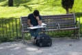 Student prepares for classes on street sitting on bench