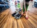 Young woman measuring multiple comfortable Crocs shoes inside the dedicated Crocs store - wooden parquet floor