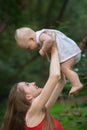 Mother playing with newborn baby on nature background. Happy motherhood concept. Vertical frame