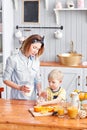 The boy drinks milk from a glass. Mother and son are smiling while having a breakfast in kitchen. Mom is pouring milk Royalty Free Stock Photo