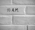 10 A.M. WRITTEN ON WHITE PLAIN BRICK WALL