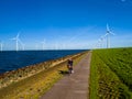 A ma cycling along a path beside the Ijsselmeer lake, with windmill turbines in Spring Royalty Free Stock Photo