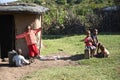 Maasai children sitting on a bench near traditional adobe house