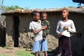 Maasai children walk in the courtyard near traditional adobe house