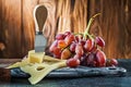 Maasdam cheese knife on little cutting board and rose grape on wooden background