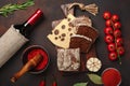 Maasdam cheese sliced on a cutting board with cherry tomatoes, black bread, garlic and rosemary, bottle of wine, wine glass on Royalty Free Stock Photo