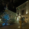 Square of the statue of Mestreechter Geis with an illuminated Christmas tree and decorated street in Maastricht in the Stokstraat