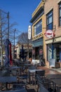 Macâs Chophouse with a red brick sidewalk lined with shops, restaurants and bars with tables and chairs on the sidewalk Royalty Free Stock Photo