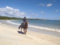 Young man riding a horse on the shore of the Caribbean Sea with calm waters, tropical