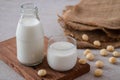 Macadamia milk in glass and bottle of macadamia on wooden board