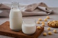 Macadamia milk in glass and bottle of macadamia milk on wooden board