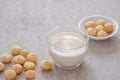 Macadamia milk in glass and macadamia nuts on table