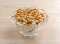 Macadamia nut pieces in a glass bowl on wood table