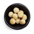 Macadamia Nuts in Black Bowl Overhead View Isolated on White Royalty Free Stock Photo