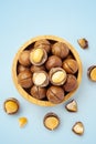 Macadamia nuts with broken nutshell in wood bowl on blue background, top view Royalty Free Stock Photo