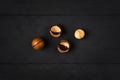 Macadamia nuts - peeled and unpeeled - on a dark wooden background