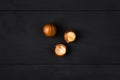 Macadamia nuts - peeled and unpeeled - on a dark wooden background