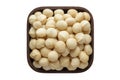 Macadamia nuts peeled in square bowl isolated on white background. organic food, top view